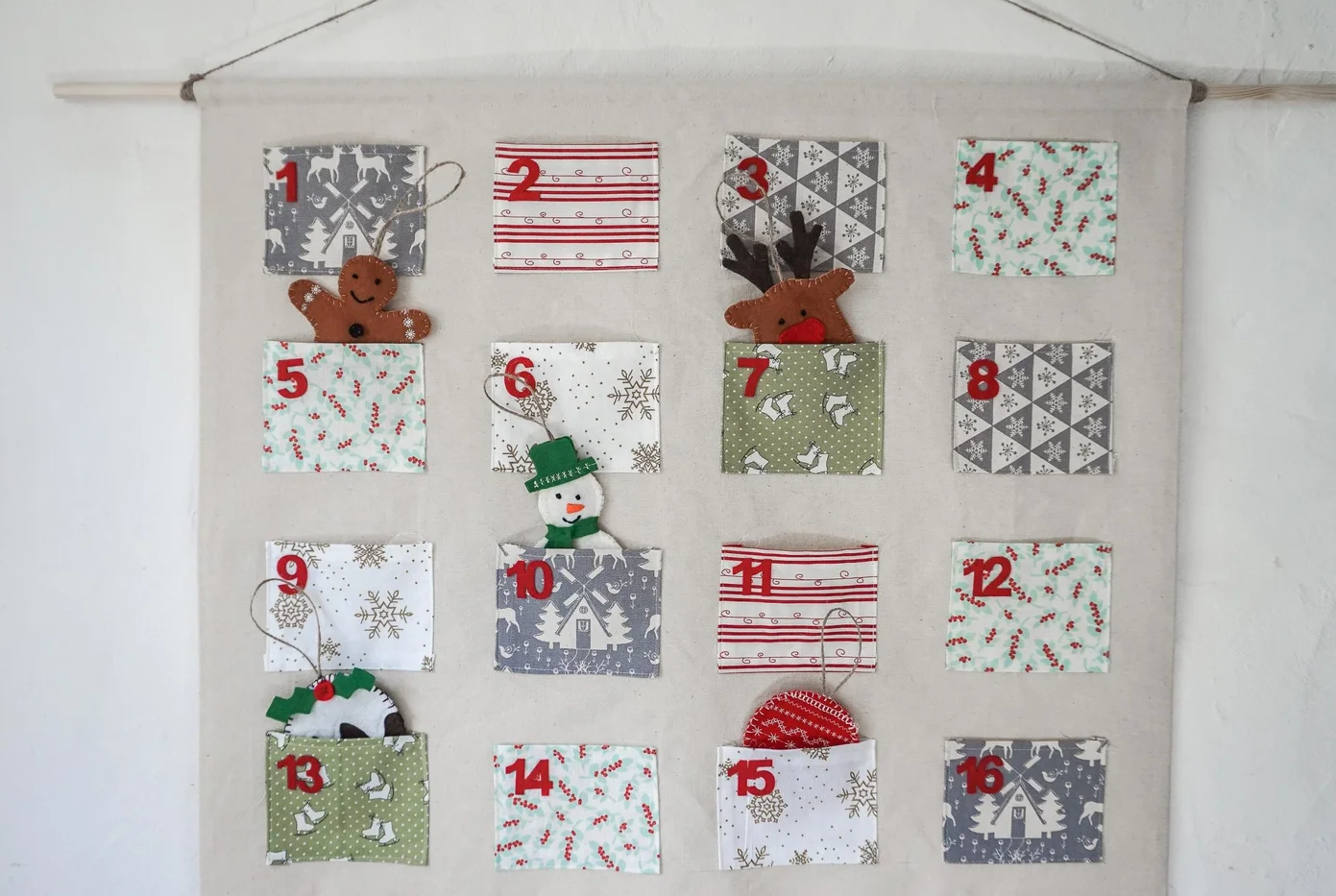 An eco friendly fabric advent calendar with 24 pockets hanging on a wall
